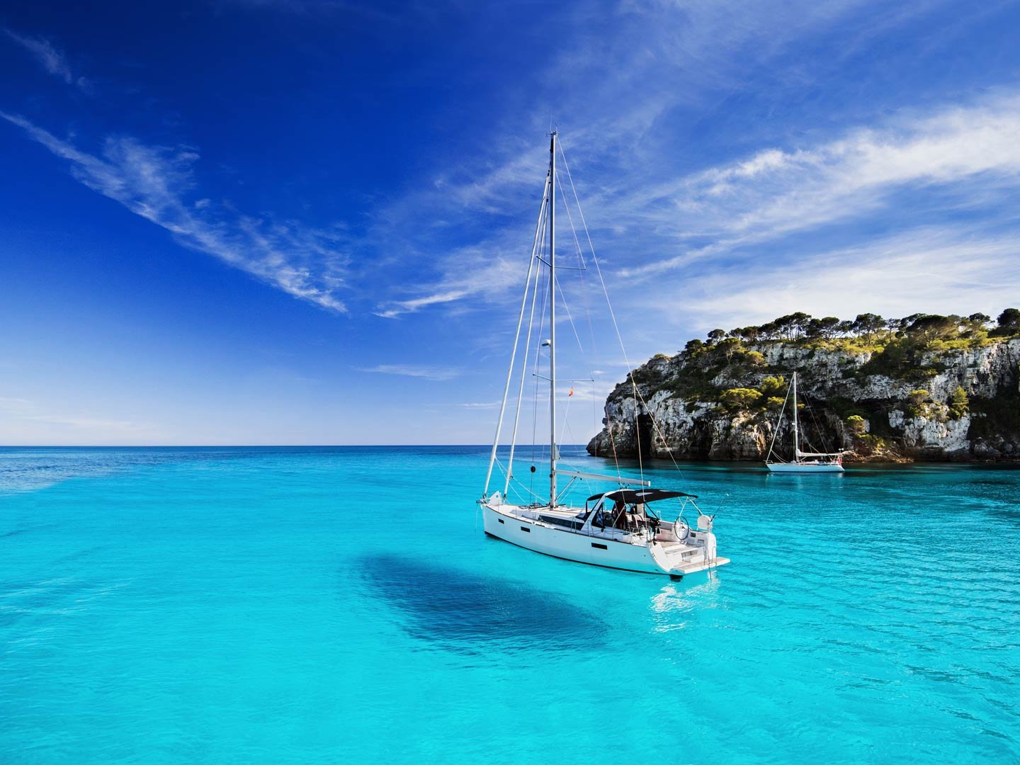 Sailboat beside Cyprus cliffs on turquoise water